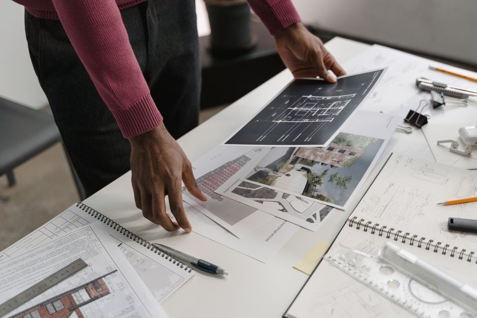 Architect evaluates blueprints on a desk, showcasing modern workspace creativity and design.